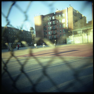 A hockey game being played on an asphalt court on Houston Street